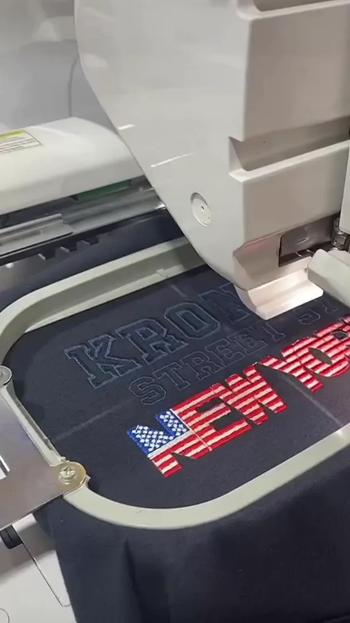 Máquina bordando un diseño sobre tejido sujeto en un bastidor
