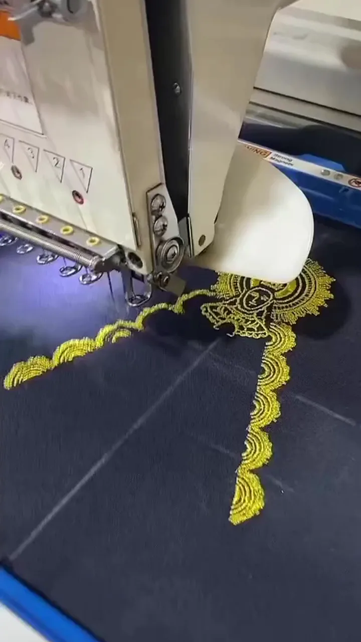 Aguja de bordado trabajando un motivo amarillo sobre tejido oscuro