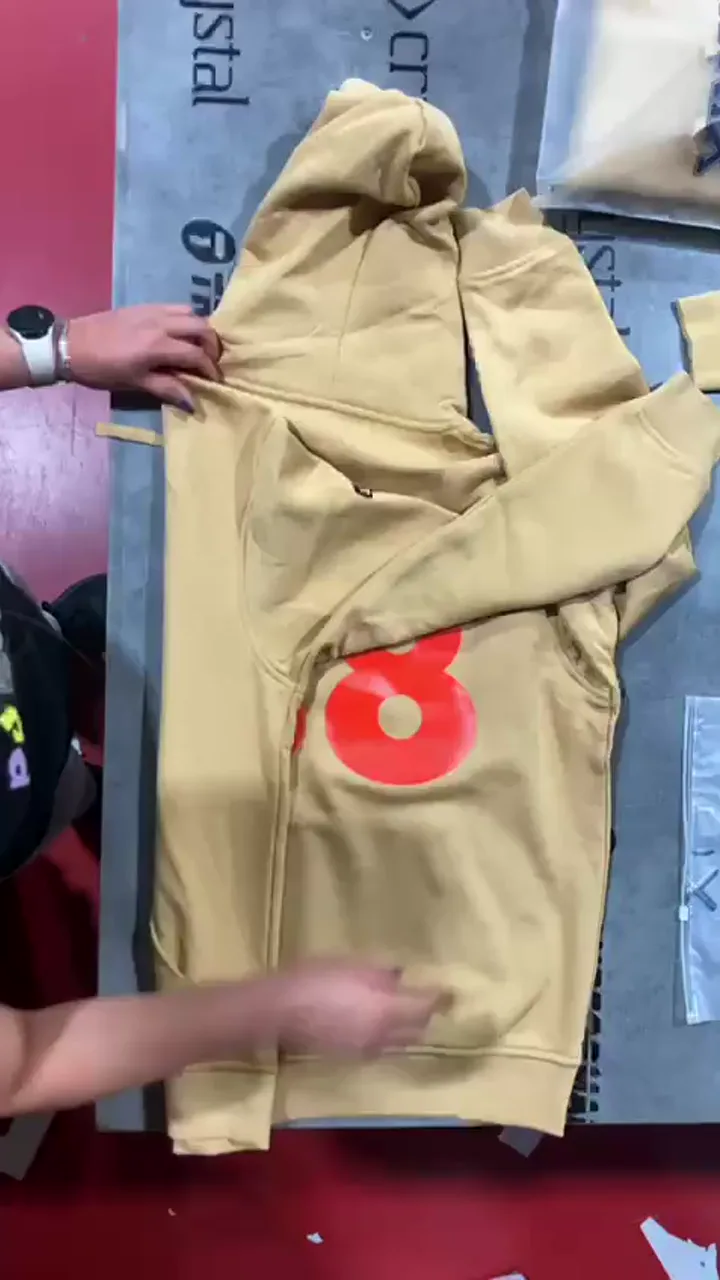Manos extendiendo una sudadera beige con un número rojo